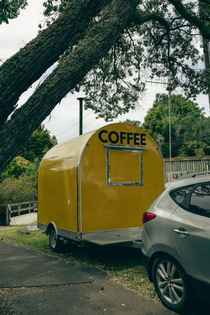 A yellow coffee trailer parked next to a car