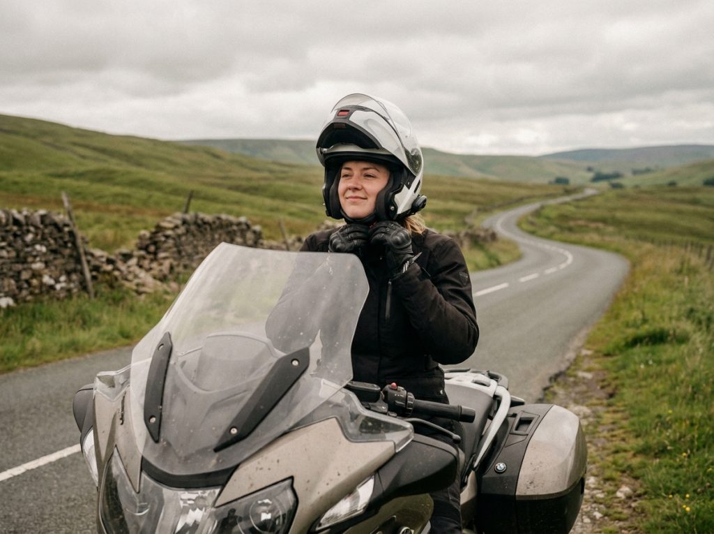 Motarde ajustant son casque intégral avant de reprendre la route lors d'un road trip à la campagne