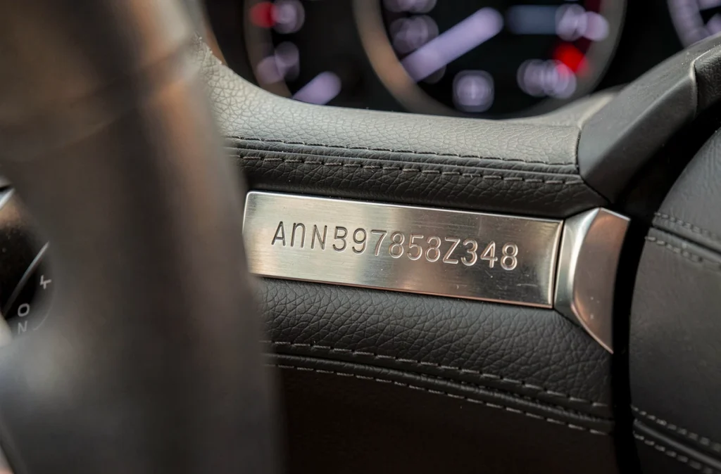 Gros plan sur la plaque d'identification VIN gravée sur le tableau de bord d'une voiture moderne