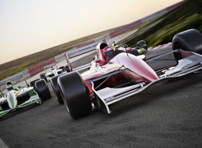 Red race car close up front view on a track leading the pack with motion Blur