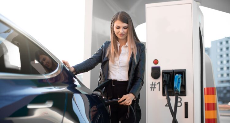 woman in formal clothes, charging an electric vehicle